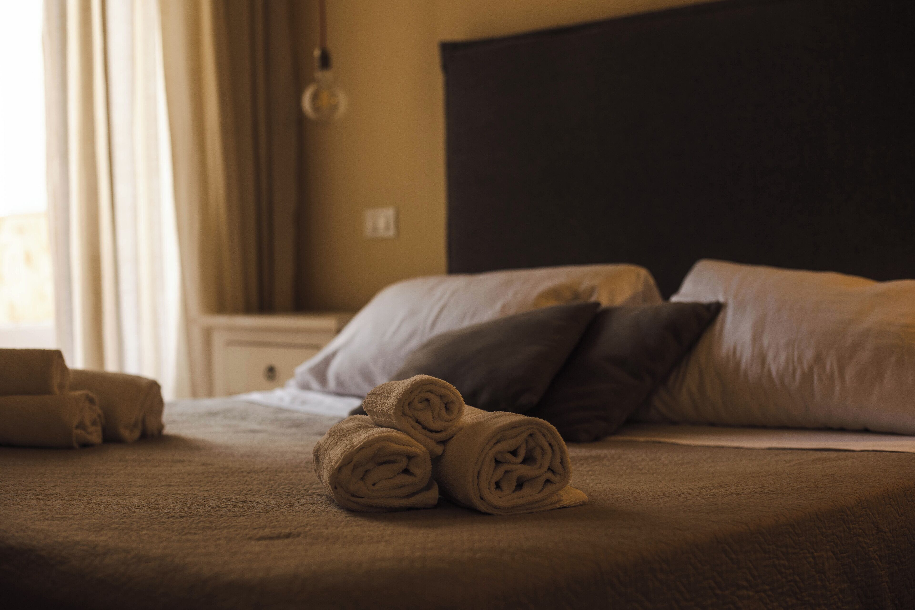 A neatly made bed with rolled towels and pillows in a hotel room.