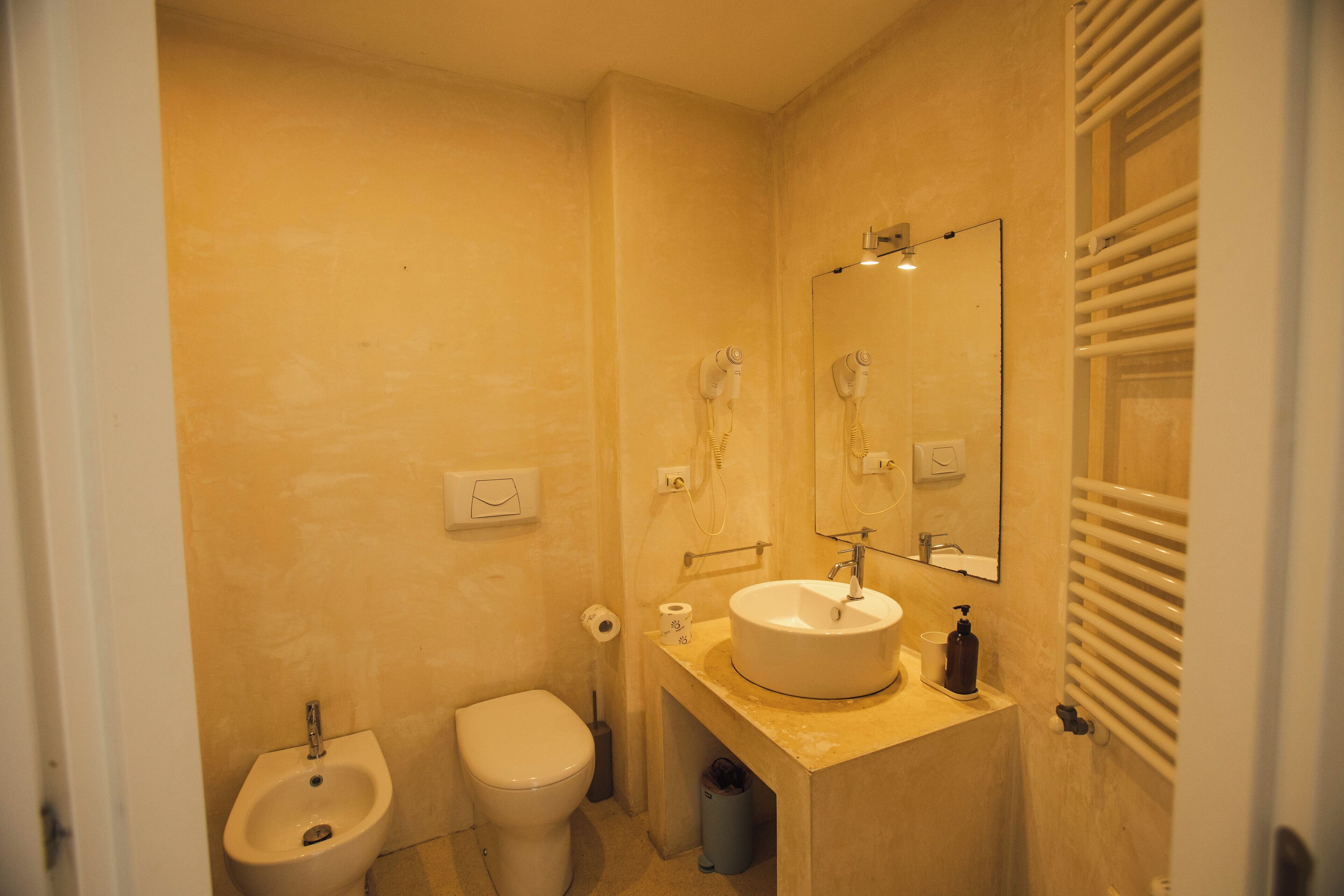 A bathroom with a bidet, toilet, sink, and mirror.