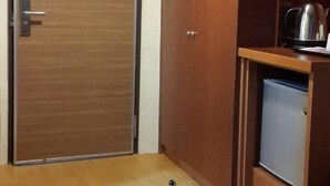 A room with a wooden door, a wardrobe, a small kitchenette with a kettle, and a whiteboard. - Long Siang Hotel (Kaohsiung)
