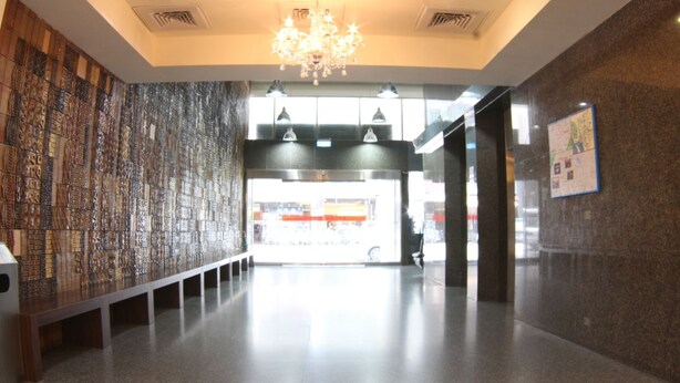 A hallway with a patterned wall, a chandelier, and a view into a shop area. - Long Siang Hotel (Kaohsiung)