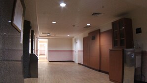 A hallway with wooden flooring, a door at the end, and a cabinet with a mirror. - Long Siang Hotel (Kaohsiung)