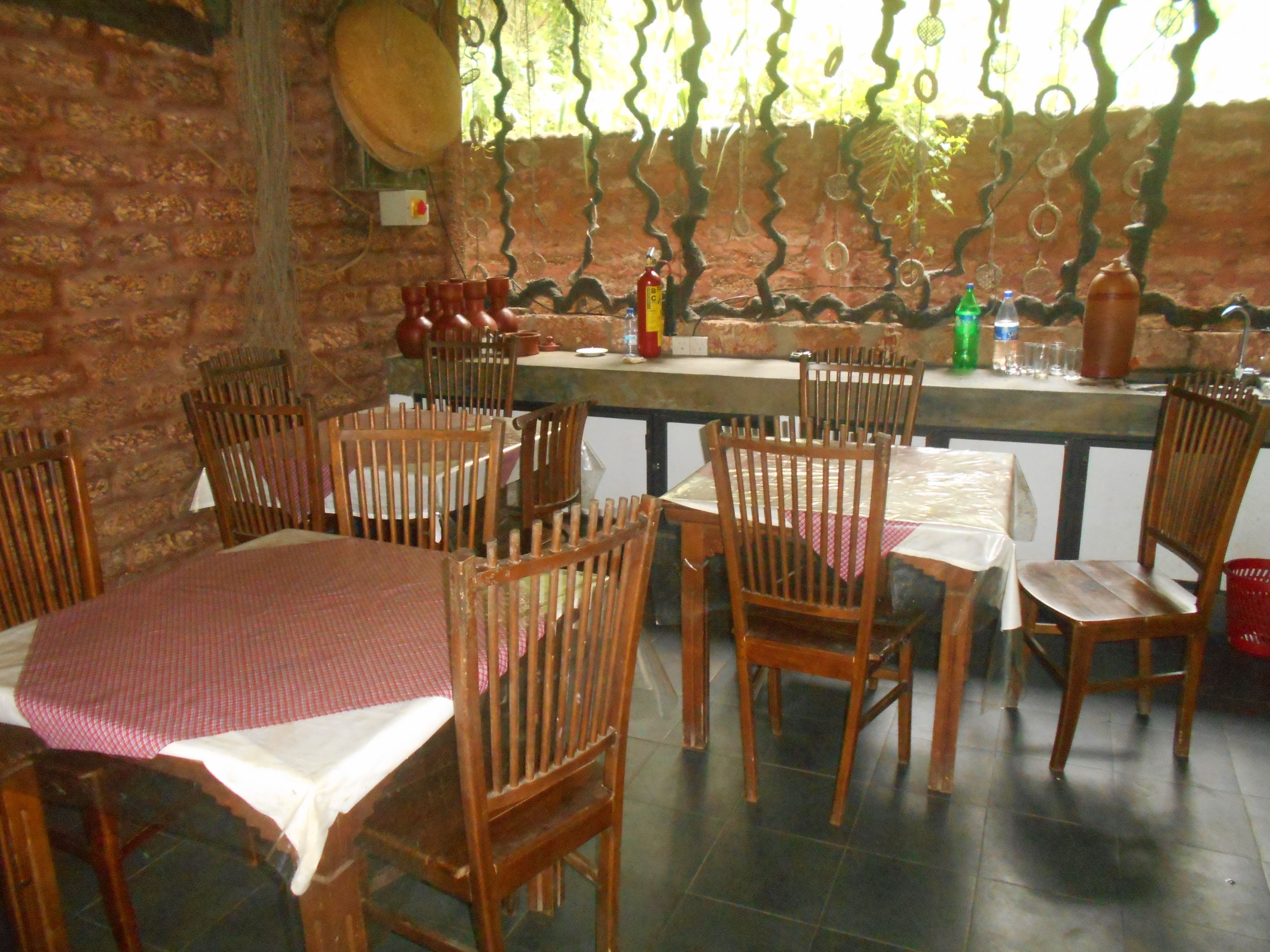 A restaurant with wooden chairs and tables, a brick wall, and a decorative metal fence.