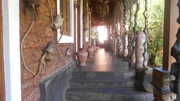 Stroll through the serene walkway, lined with natural elements and vases, leading to a cozy interior space.