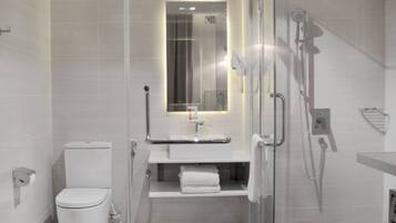 Un baño moderno con ducha de vidrio, inodoro y lavabo con espejo arriba.
