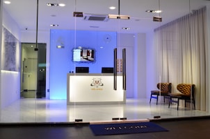 A reception area with a glass partition, a reception desk with a logo, and two upholstered chairs.