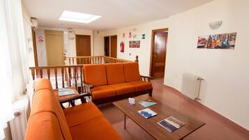 A hotel lobby with orange seating, a wooden coffee table, and a staircase leading to another floor.