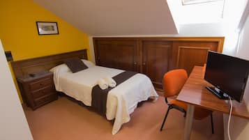 Un dormitorio con cama, escritorio con computadora y armario.