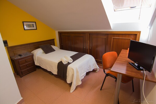 Un dormitorio con cama, escritorio con computadora y armario.