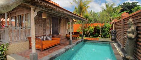 A pool area with a wooden deck, a bench, and a statue.