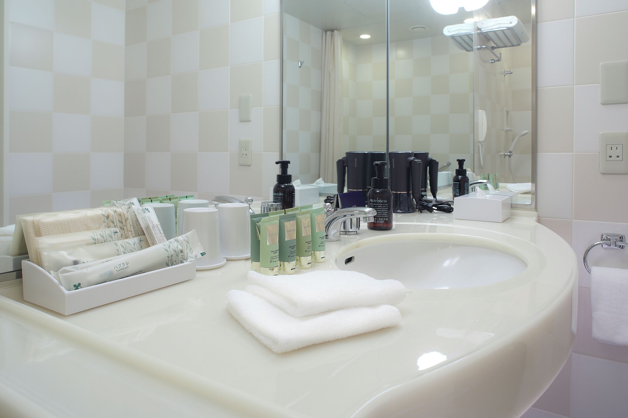 A bathroom with a large mirror, a sink, and toiletries.