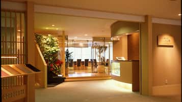 A reception area with a reception desk, a staircase, and a potted plant.