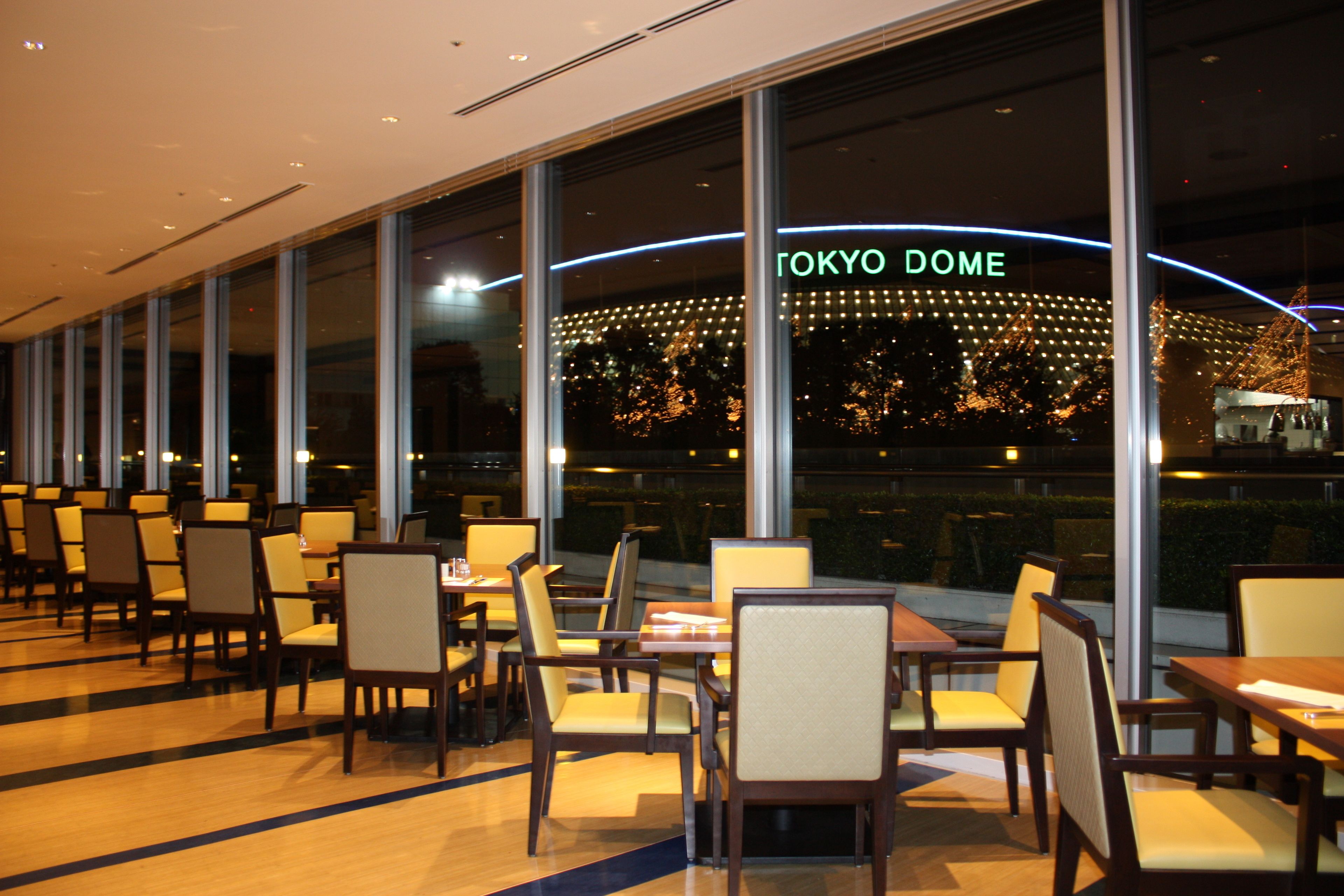 A restaurant with a view of Tokyo Dome, featuring rows of tables and chairs.