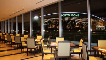 A restaurant with a view of Tokyo Dome, featuring rows of tables and chairs.