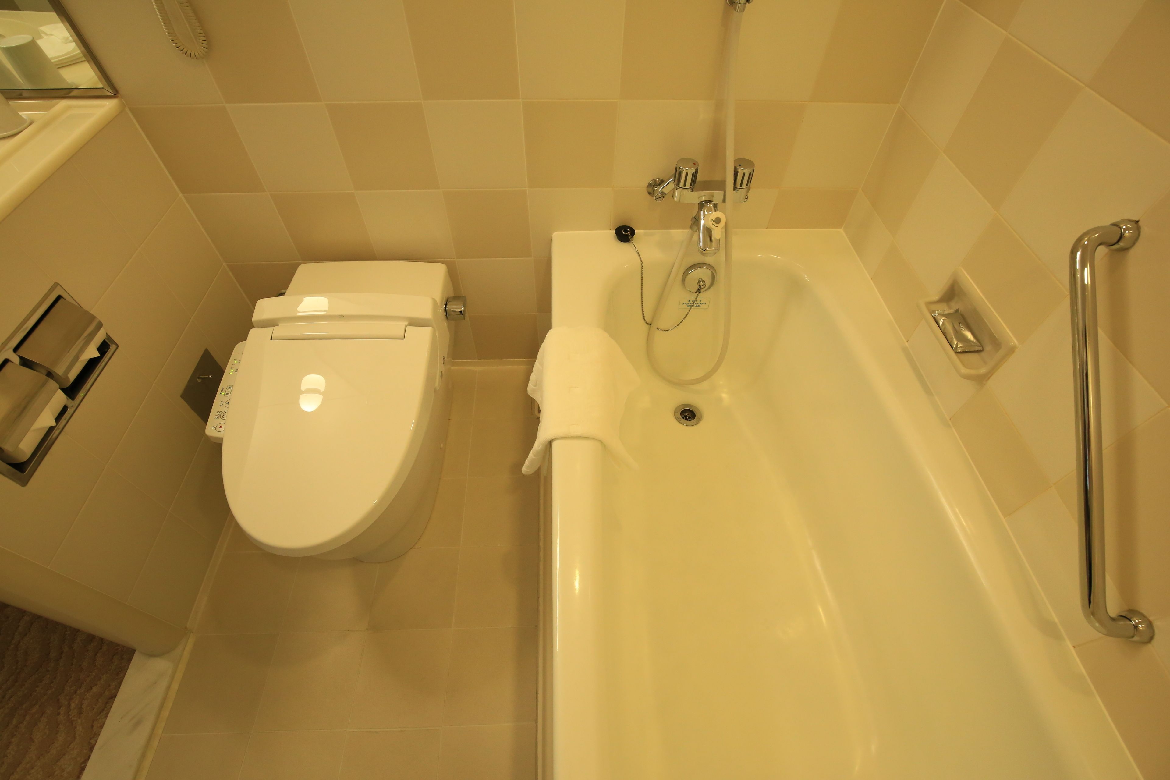 A bathroom with a toilet, a bathtub, and a handrail.