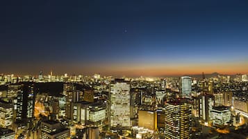 Paisagem urbana noturna com diversos edifícios altos, janelas iluminadas e uma estrutura urbana densa.