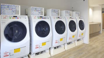 Uma fileira de máquinas de lavar roupa de carregamento frontal brancas, com painéis de controle e instruções de segurança.