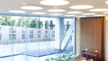 Un espacio interior amplio con varias disposiciones de asientos, incluyendo sillas y mesas, y un elemento decorativo central.