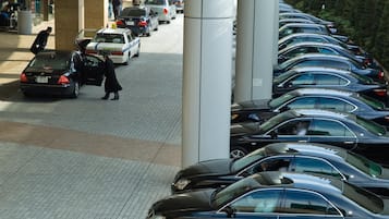 A parking area with multiple cars, a person walking, and a building entrance.