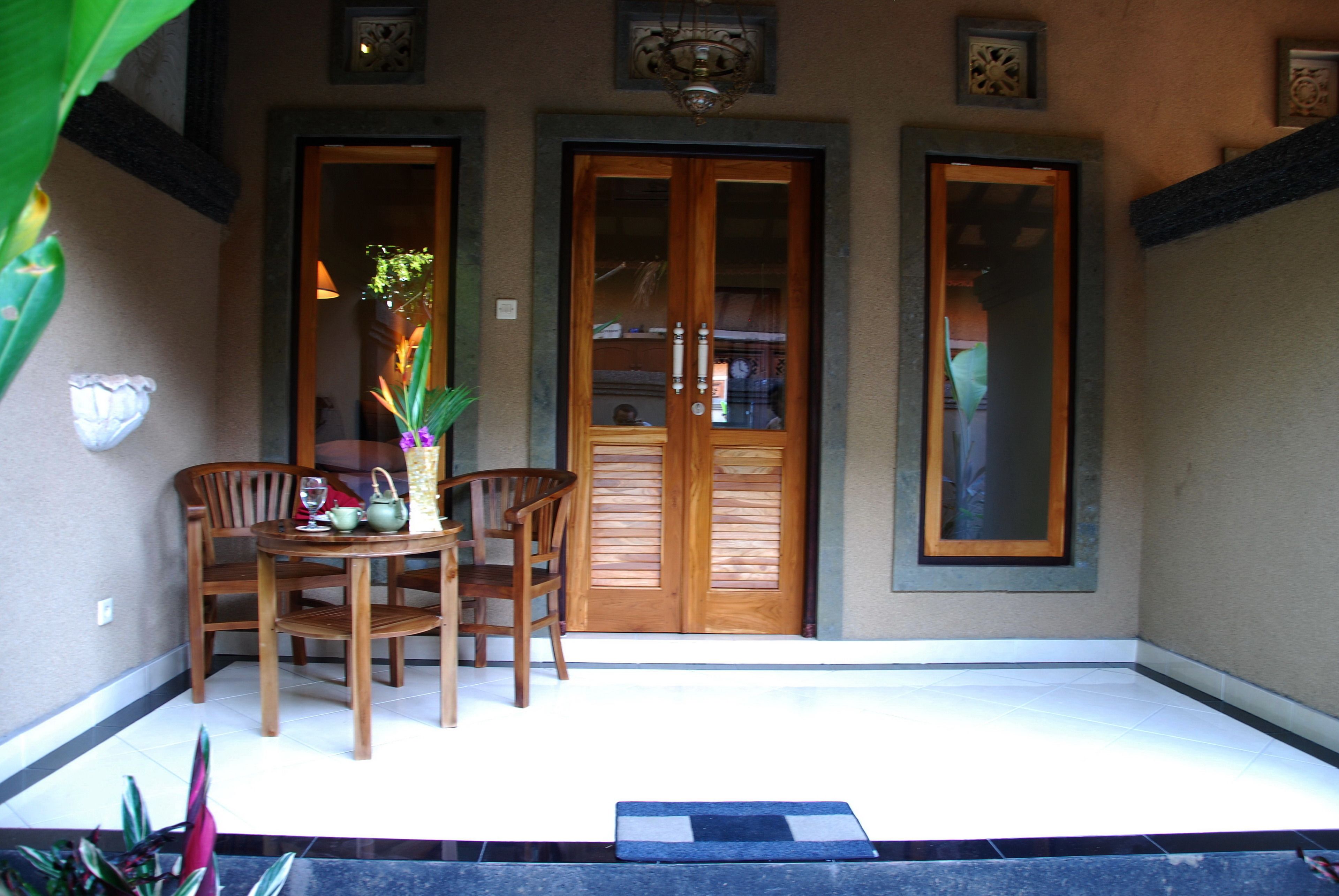 A wooden dining table with chairs, a vase with flowers, and a small table lamp.