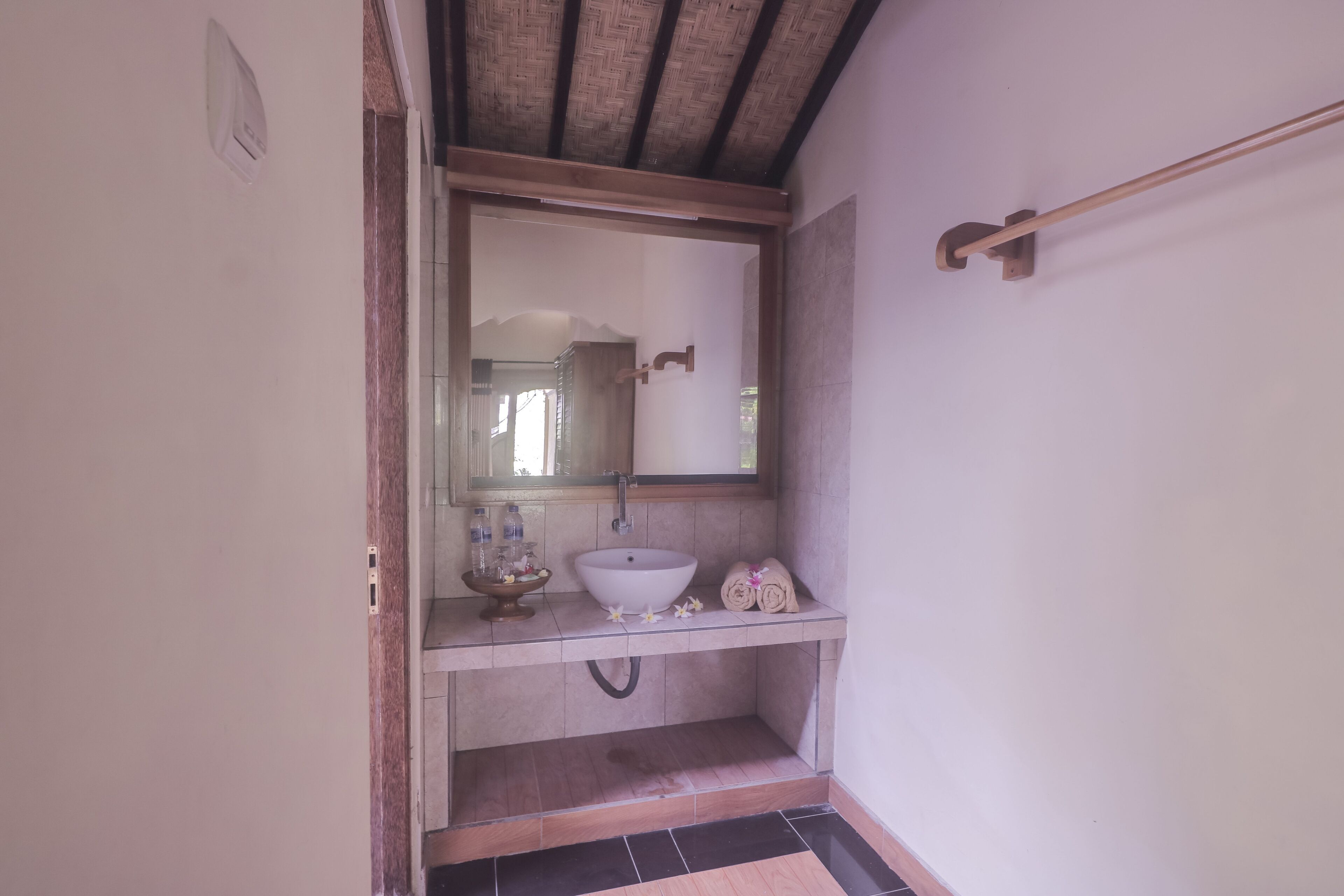 Un bagno con un lavandino bianco, uno specchio e un portascopino.