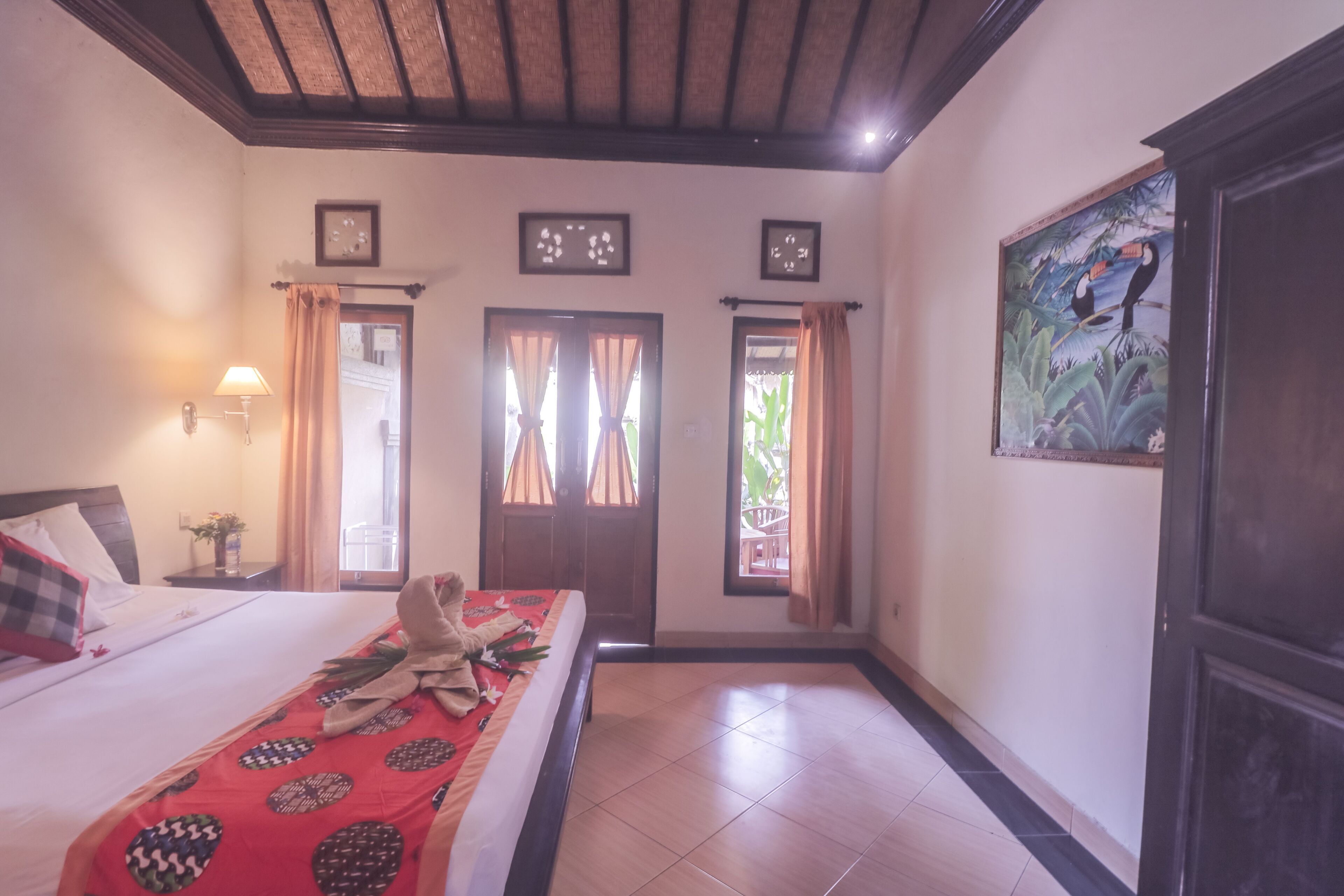 Une chambre d’hôtel avec un lit, des rideaux, un tableau et un plafond en bois.