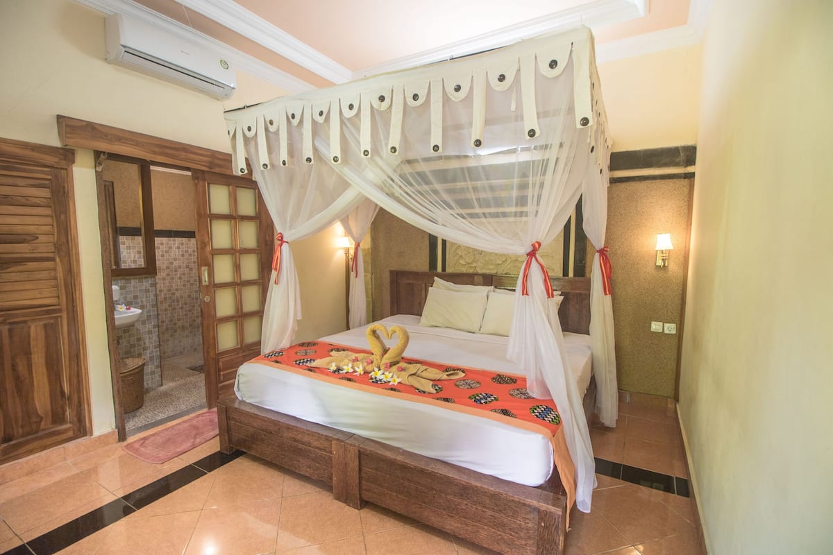 A four-poster bed with a canopy, a wooden headboard, and a floral bedspread.