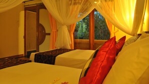 A hotel room with two beds, sheer curtains, and a view of greenery outside. - Trijaya Guest House (Pemuteran)