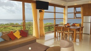 Um quarto espaçoso com uma grande janela que oferece uma vista panorâmica, uma área de jantar com móveis de madeira e uma televisão de tela plana na parede.