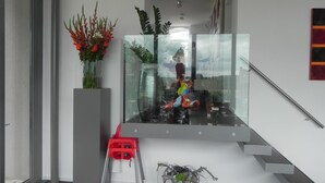 A modern interior with a staircase, a red child’s chair, and a potted plant. - Hotel Restaurant Uit de Kunst (Vijlen)