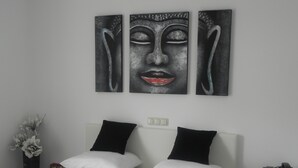 A hotel room with a bed, two black pillows, a white headboard, a nightstand with a phone, and a wall-mounted artwork. - Hotel Restaurant Uit de Kunst (Vijlen)