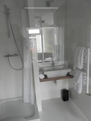 Un baño moderno con cabina de ducha de vidrio, un lavamanos blanco y un perchero para toallas.