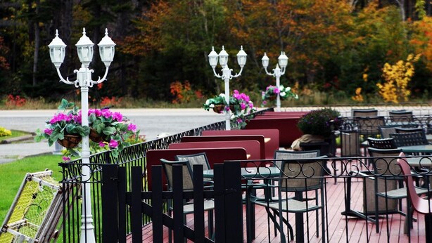 Outdoor seating with tables and chairs, surrounded by a fence and decorative street lamps. - The Mountain View Motel & Cottages (Pleasant Bay)