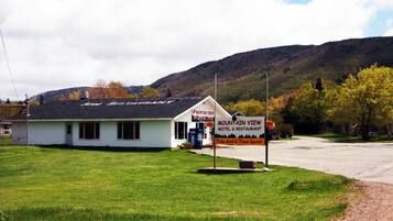 Een motel en restaurant genaamd Mountain View, met een eenvoudig wit gebouw en een zwart dak, een Pepsi-koelkast en een bord waarop dagelijkse lunch- en dinerspecials worden aangeboden.