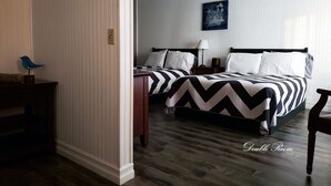 A double room with two beds, a nightstand, a lamp, and a wall-mounted artwork. - The Mountain View Motel & Cottages (Pleasant Bay)