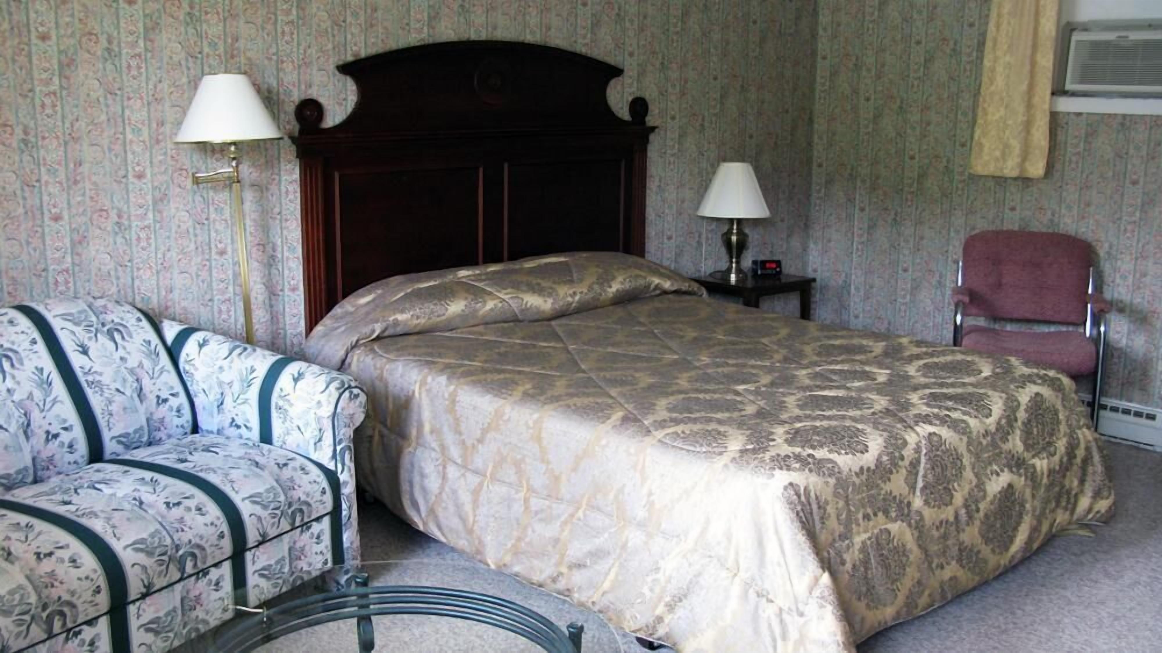 A bedroom with a bed, a chair, and two lamps.