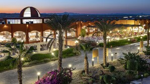 A hotel with a large central dome, multiple dining areas, and a landscaped garden with palm trees. - Three Corners Happy Life Beach Resort - All Inclusive (Marsa Alam)
