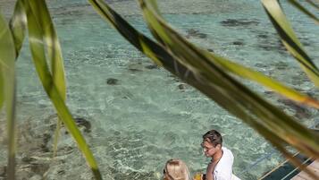 A wooden deck overlooking clear turquoise water with visible rocks and a distant shoreline.