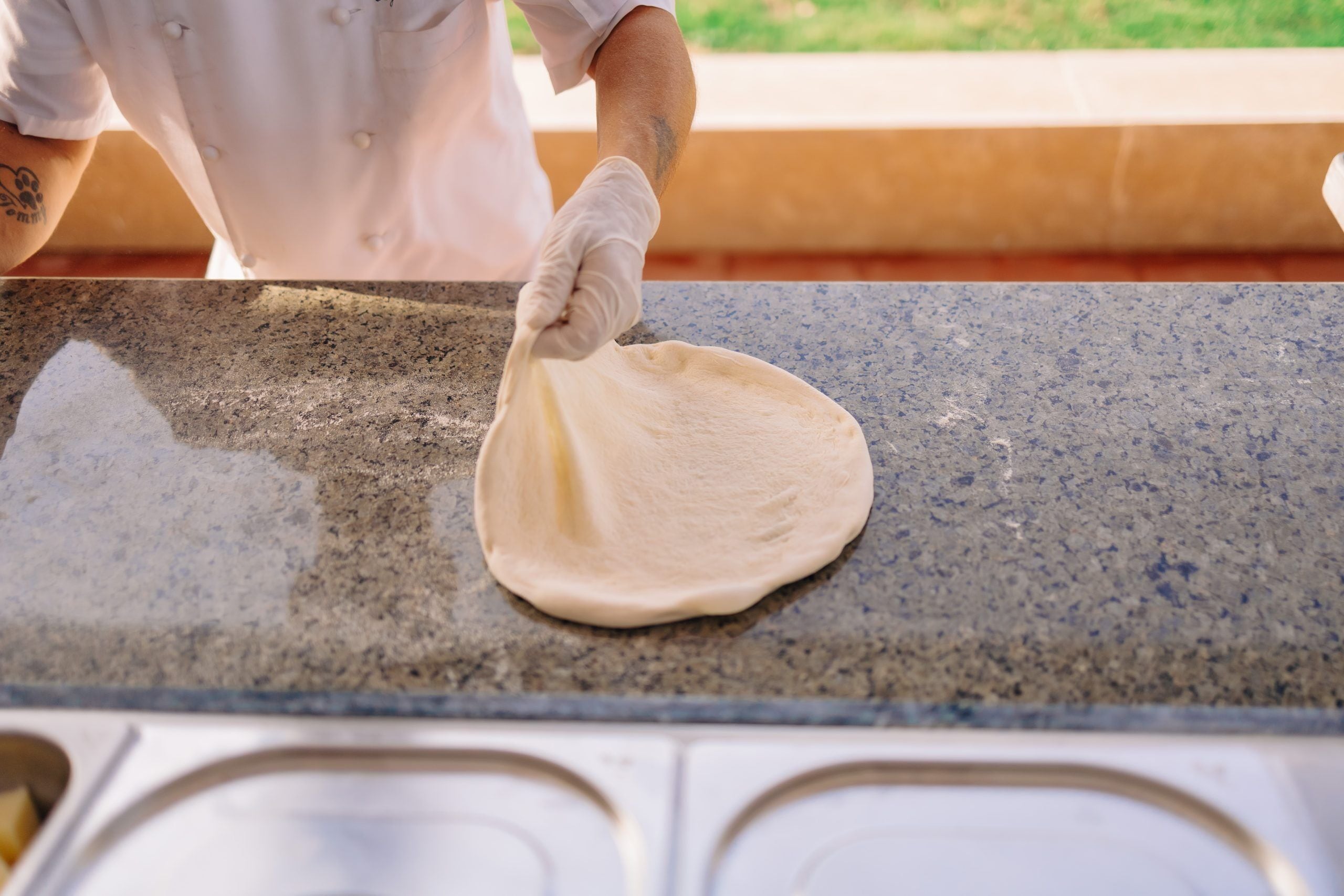 Une personne qui étale de la pâte sur un plan de travail en granit.