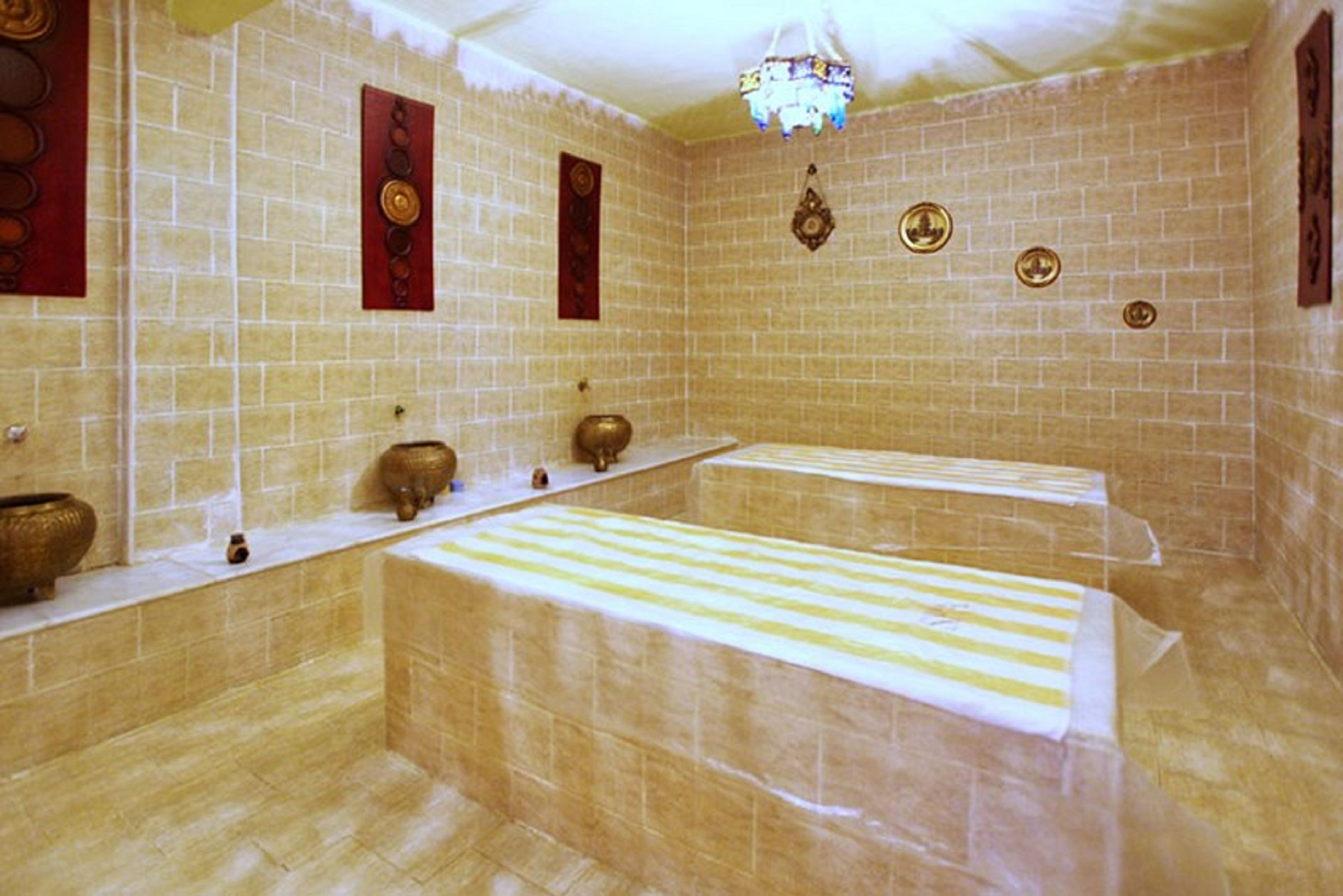 Ein traditionelles Badezimmer mit gefliesten Wänden, einer Sitzbank in der Mitte und dekorativen Elementen.
