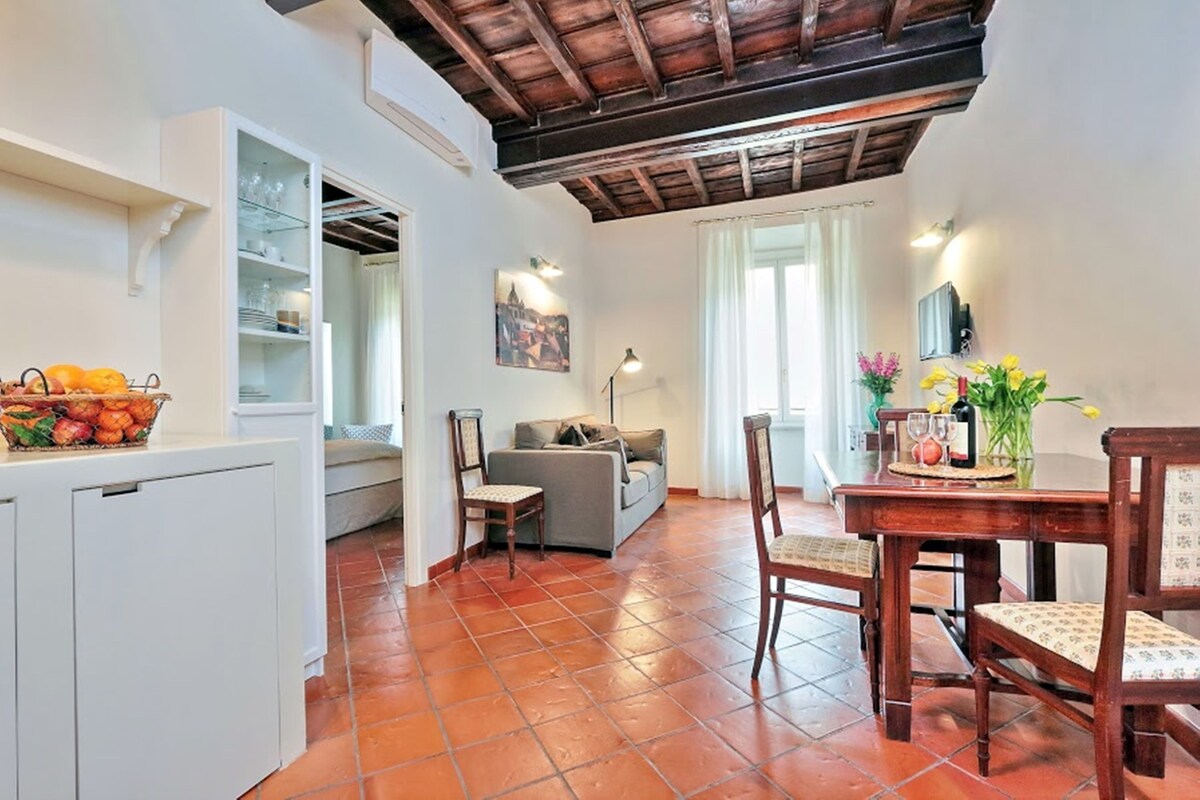 Una cocina con comedor, un refrigerador, una mesa con sillas y un sofá.