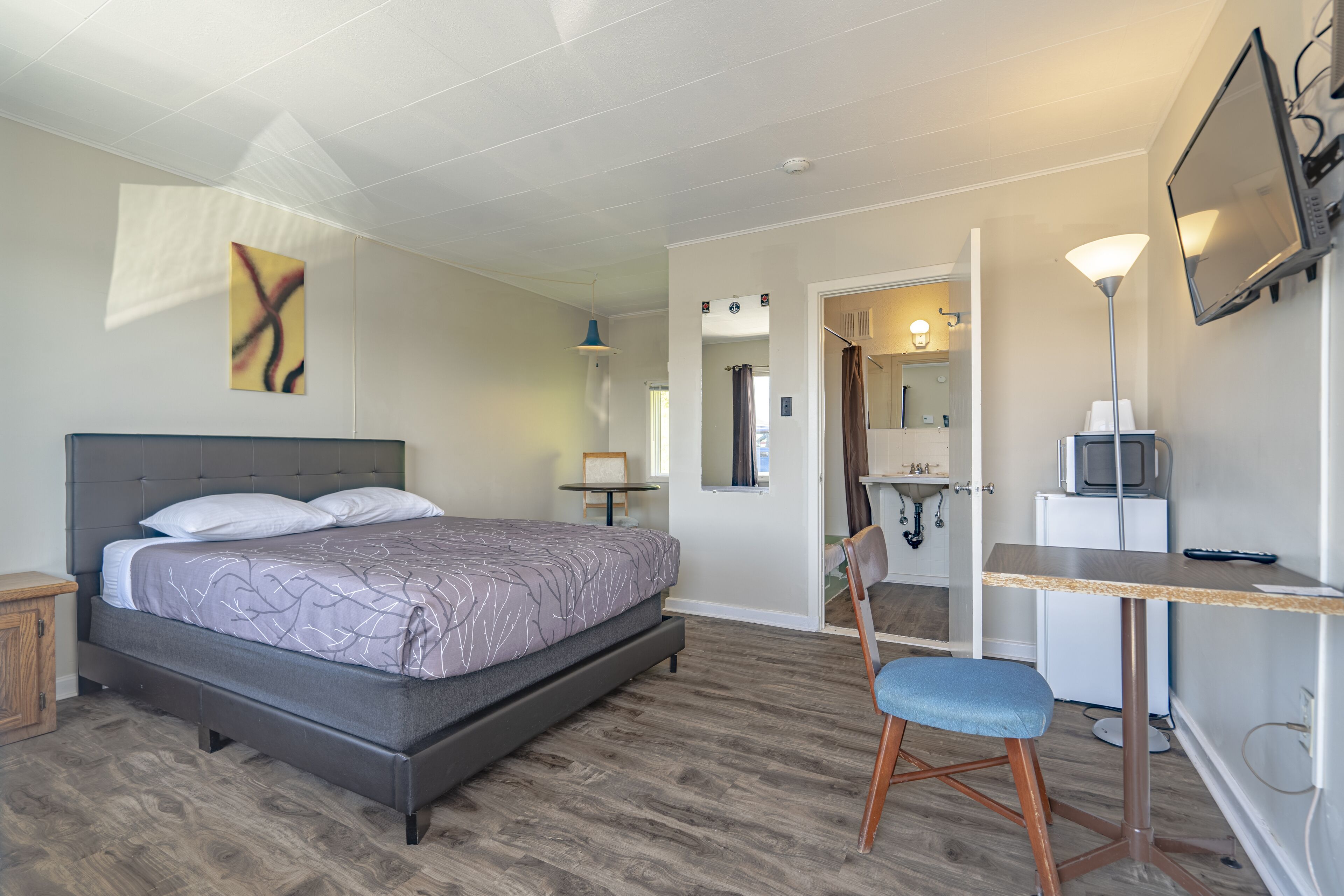 Une chambre à coucher avec un lit, un bureau, une chaise et un téléviseur.