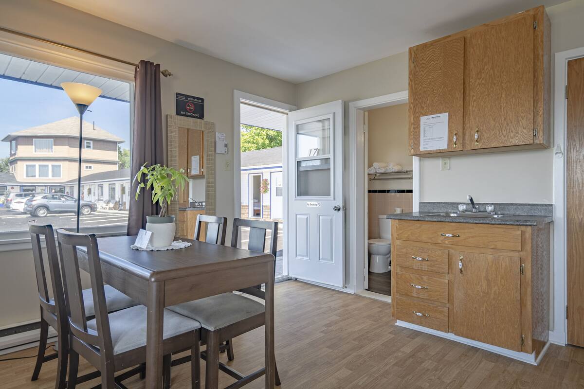 Una cocina moderna con armarios de madera, una mesa de comedor con sillas y vistas a la calle.