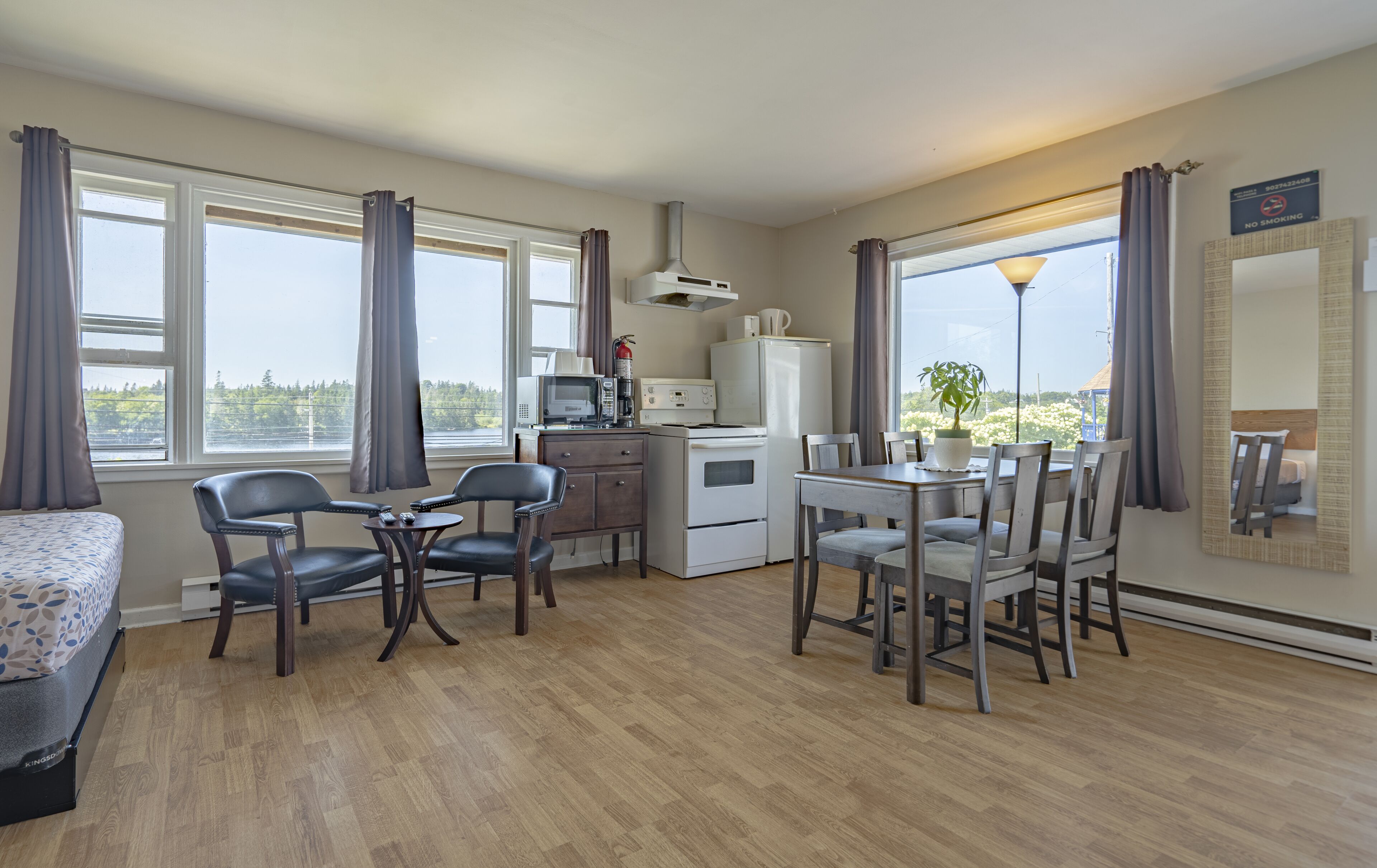 A compact hotel room with a kitchenette, a dining area, and a bed.