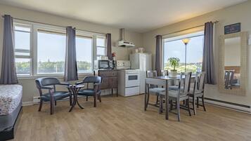 A compact hotel room with a kitchenette, a dining area, and a bed.