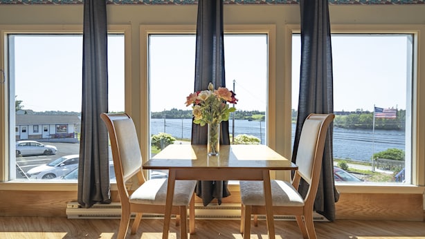 A dining area with a table, chairs, and a vase of flowers. - NovaStar Motel On The Lake (Dayton)