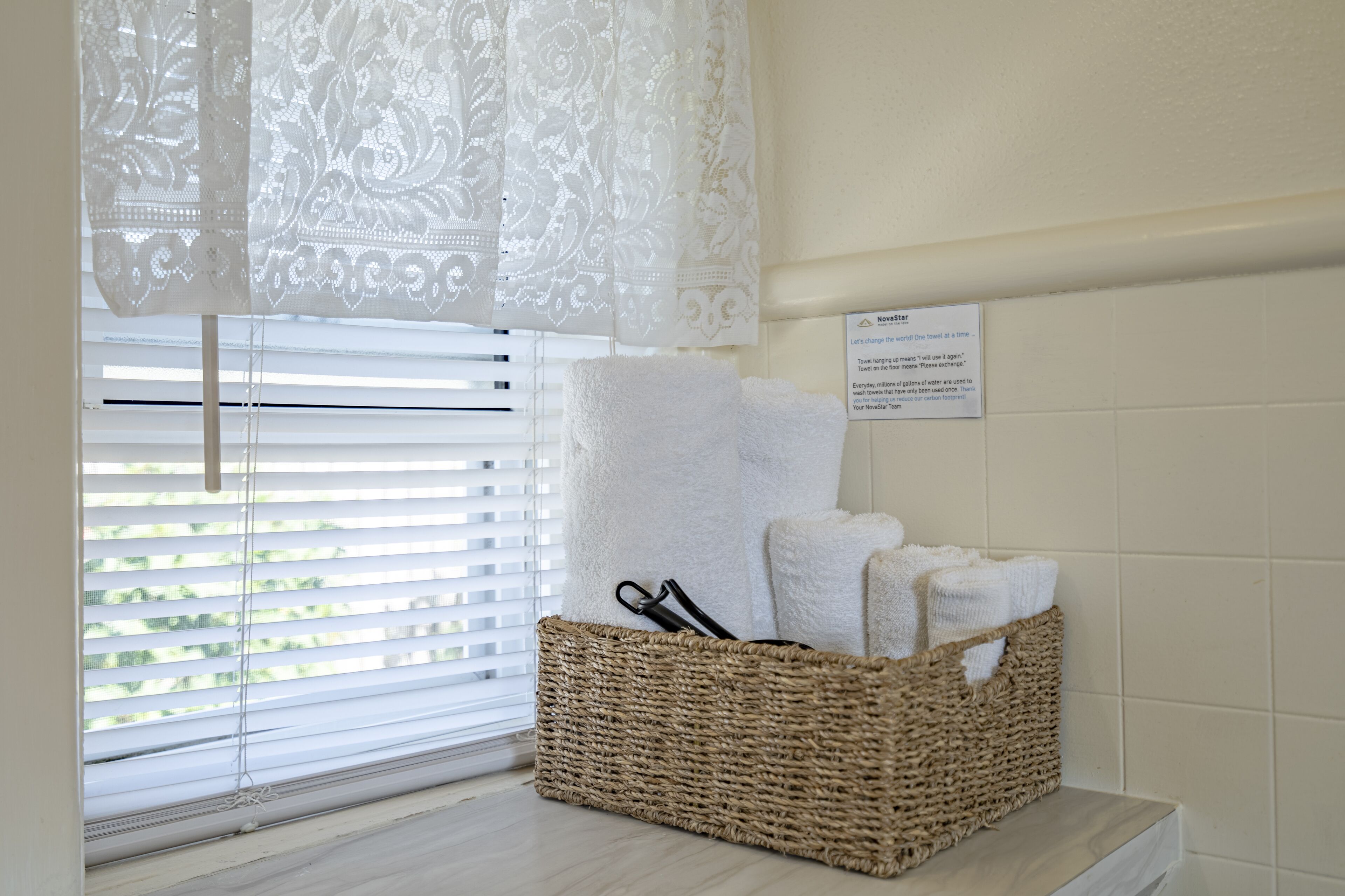 Une salle de bain avec un panier en osier contenant des serviettes et un panneau accroché au mur.