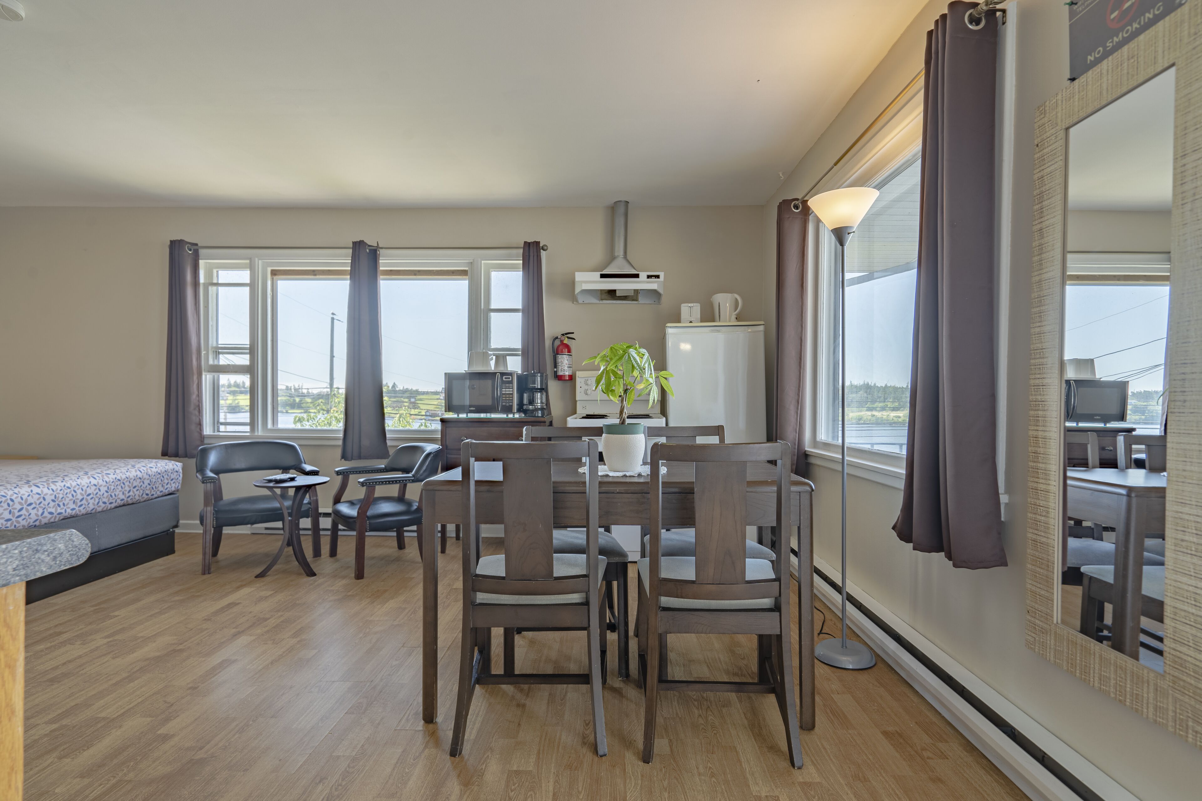 A modern hotel room with a dining area, a sofa, a desk, and a large mirror.