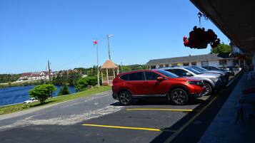 Un estacionamiento con una camioneta roja aparcada cerca de un edificio con una zona cubierta.