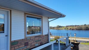 A house with a stone facade, large windows, and a view of a lake and distant buildings. - NovaStar Motel On The Lake (Dayton)