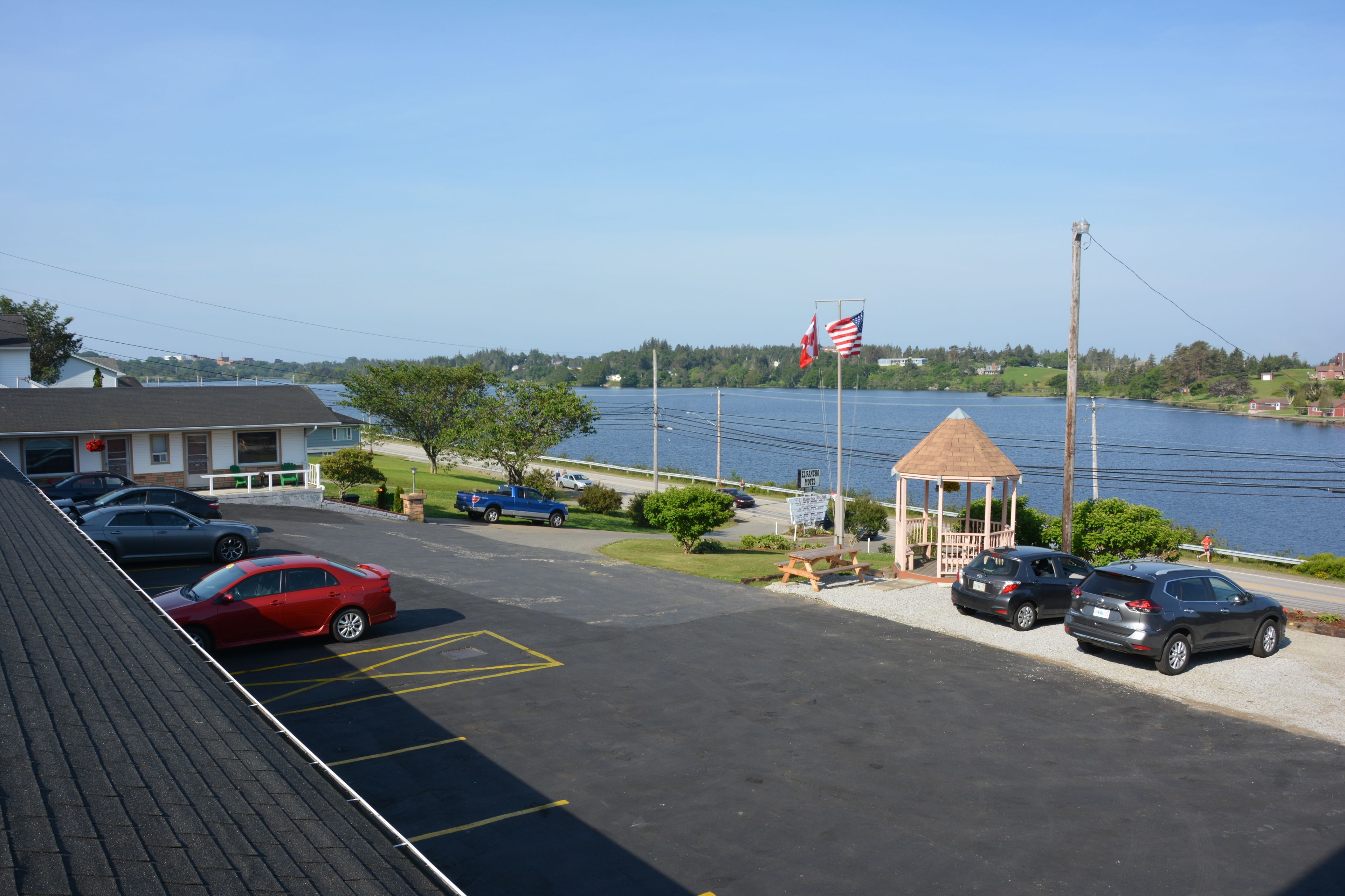 A parking lot with cars, a gazebo, and a view of a lake.